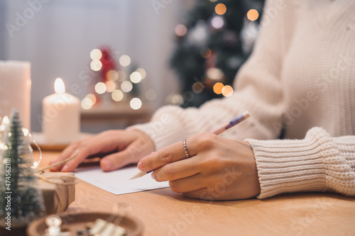 Goals plans make to do and wish list for new year christmas concept, girl writing in notebook. Woman hand holding pen on notepad at home on winter holidays xmas. Christmas decoration, gift boxes. 