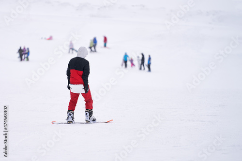A snowboarder with you (a tourist mat) on his buttocks is standing on a snow-covered mountainside. Copy space.