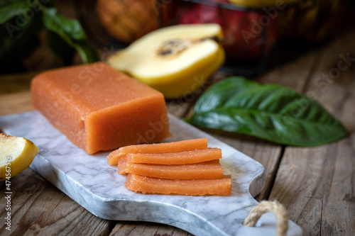 Quince marmalade, with commbert cheese, on a marble board with quince pieces.