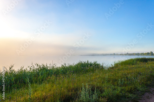 Landscape of lake in mist with sun glow at sunrise