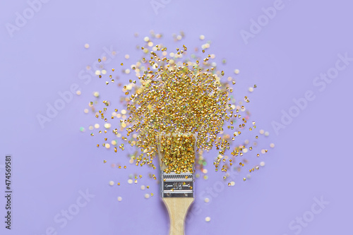 Brush with gold sparkles on a lilac background. Flat lay. The concept is to paint your day.