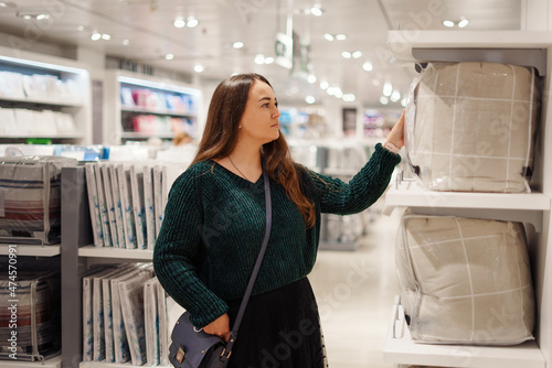 Young focused woman doing shopping in store mall in bedding department