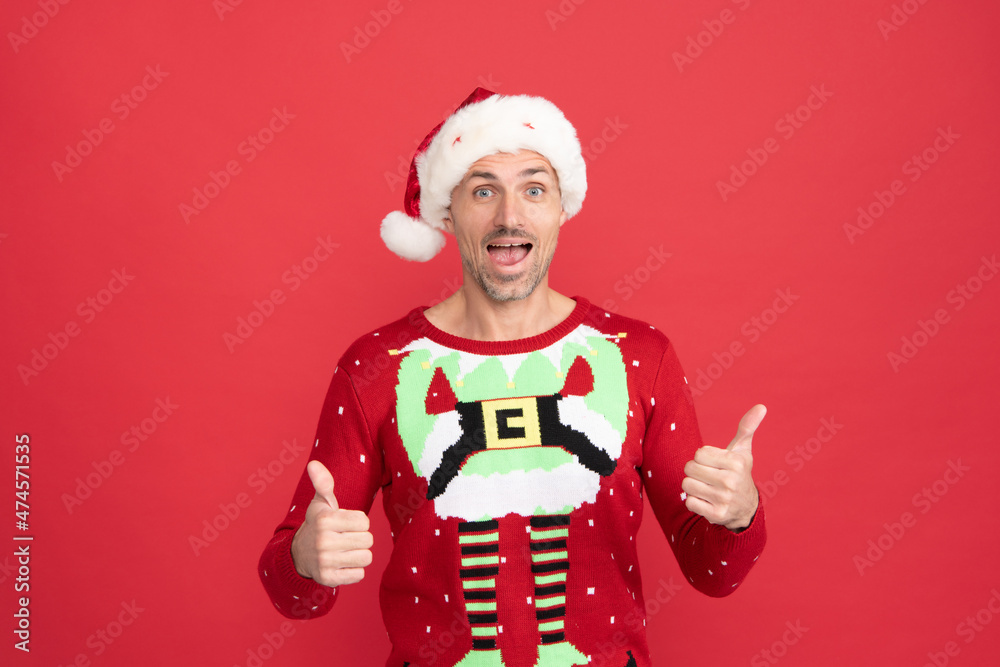 Get your Christmas surprise. Surprised man in santa hat give thumbs. Christmas elf show approval sign Get your Christmas surprise. Surprised man in santa hat give thumbs. Christmas elf show approval sign