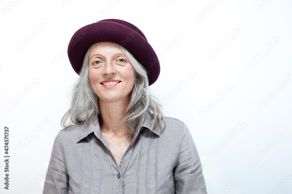 portrait of a mature woman with white hair and hat , similing, in studio and white background portrait of a mature woman with white hair and hat , similing, in studio and white background