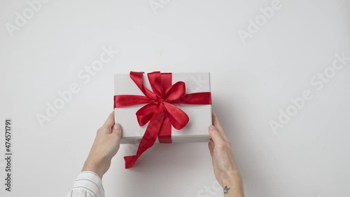 Woman hands unboxing opening empty craft gift box with red bow on the white background. Christmas, New Year, Birthday, holiday, anniversary concept. Top view, flat lay.