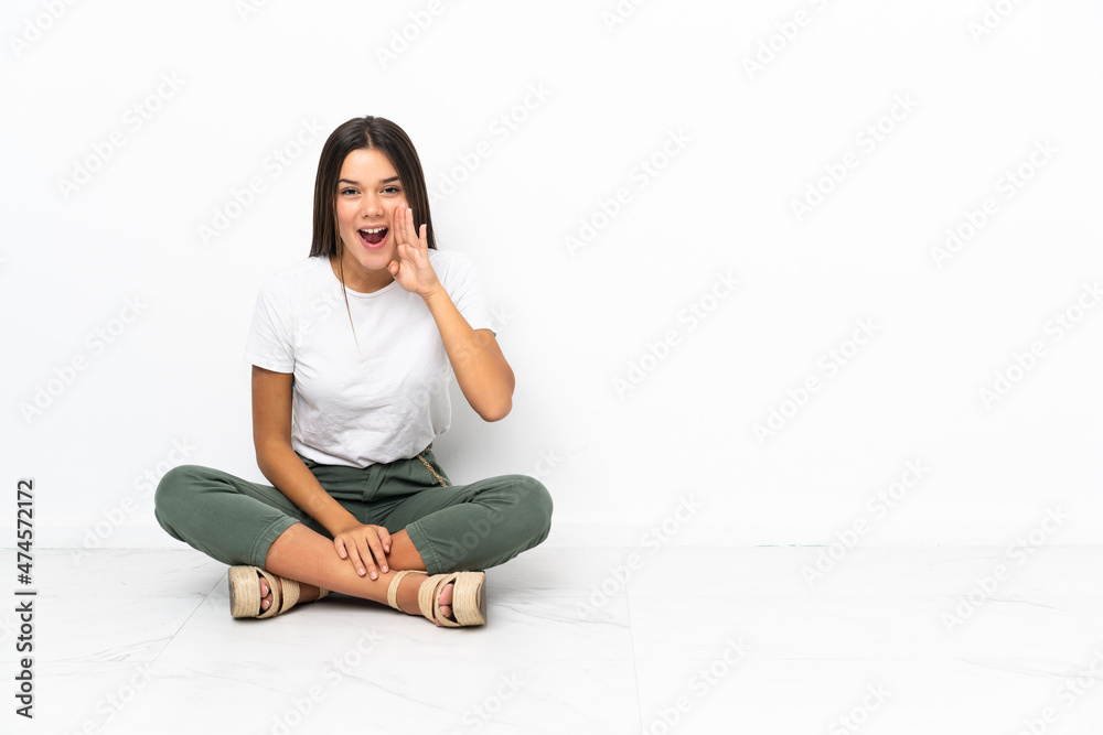 Teenager girl sitting on the floor shouting with mouth wide open Teenager girl sitting on the floor shouting with mouth wide open