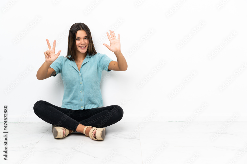 Teenager girl sitting on the floor counting eight with fingers Teenager girl sitting on the floor counting eight with fingers