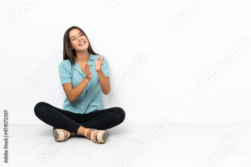 Teenager girl sitting on the floor applauding after presentation in a conference