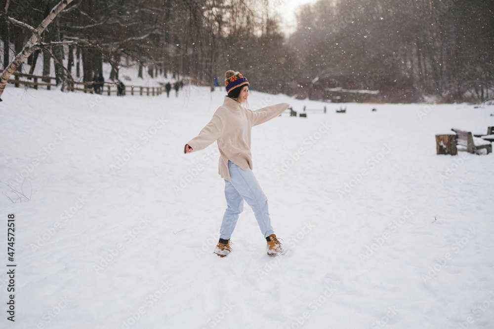 Young woman girl in sweater and funny hat cathes snowflakes, tounge out, smiles, have fun outdoor on winter day, vacation. Adorable pretty face portrait, cheerfull, happy. Winter clothing. travel 