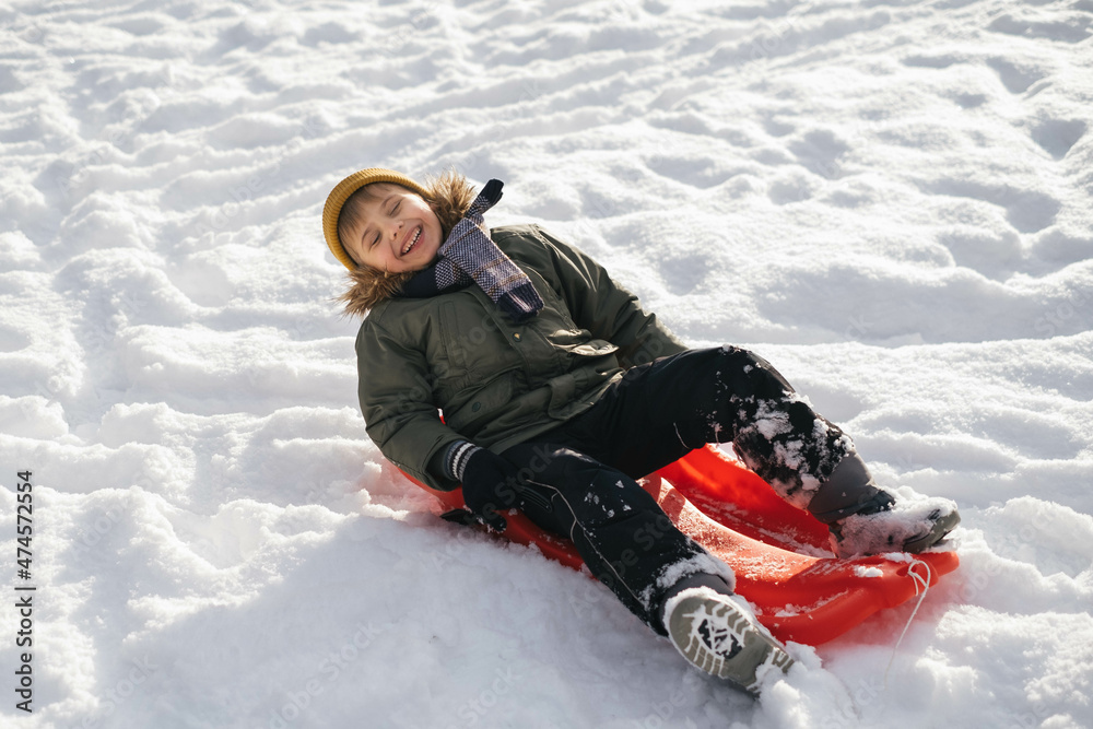 Adorable happy preschool boy riding a sled. Have fun outdoor on winter. Vacation and winter travelling. Snowy cold weather, sunny day. Hat, coat, scarf. Adorable happy preschool boy riding a sled. Have fun outdoor on winter. Vacation and winter travelling. Snowy cold weather, sunny day. Hat, coat, scarf.