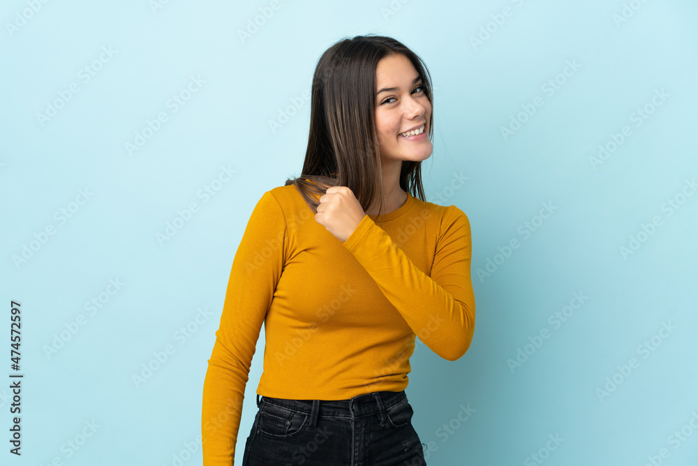 Teenager girl isolated on blue background celebrating a victory Teenager girl isolated on blue background celebrating a victory