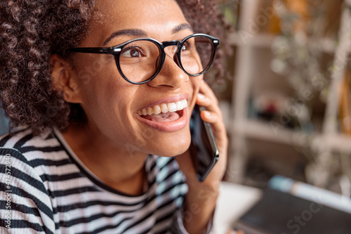 Close up of joyful lady in glasses having phone conversation and smiling expressing positive emotions