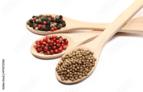 Coriander, red and colorful pepper in wooden spoon isolated on white  
