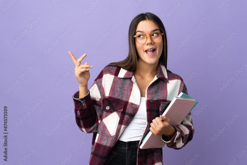 Young student woman isolated on purple background intending to realizes the solution while lifting a finger up Young student woman isolated on purple background intending to realizes the solution while lifting a finger up