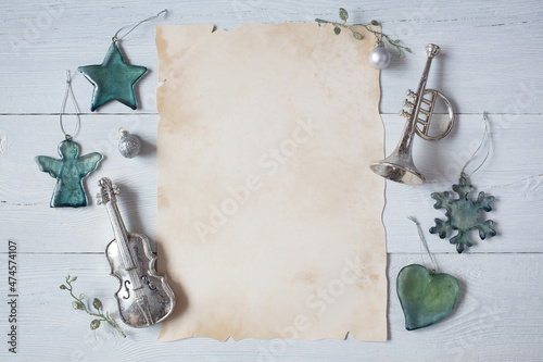 White wooden winter background with paper for text, posters, congratulations and Christmas tree decorations, wind instrument trumpet and stringed bowed violin, angel, snowflake, star, heart, balls.