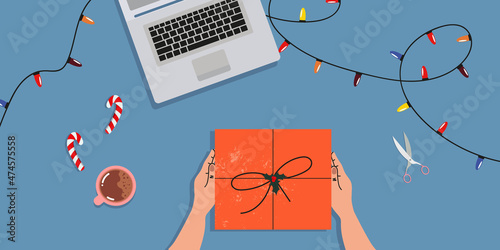 Hands and a gift on the table. Top-down view. Unpacking a gift.