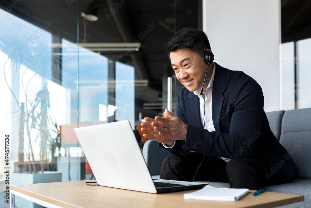 Asian call center employee talking to customers sitting in office, Asian businessman using headset and laptop for video call happy and smiling Asian call center employee talking to customers sitting in office, Asian businessman using headset and laptop for video call happy and smiling