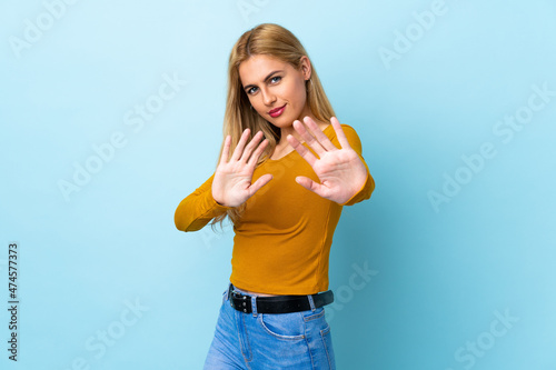 Young Uruguayan blonde woman over isolated blue background nervous stretching hands to the front