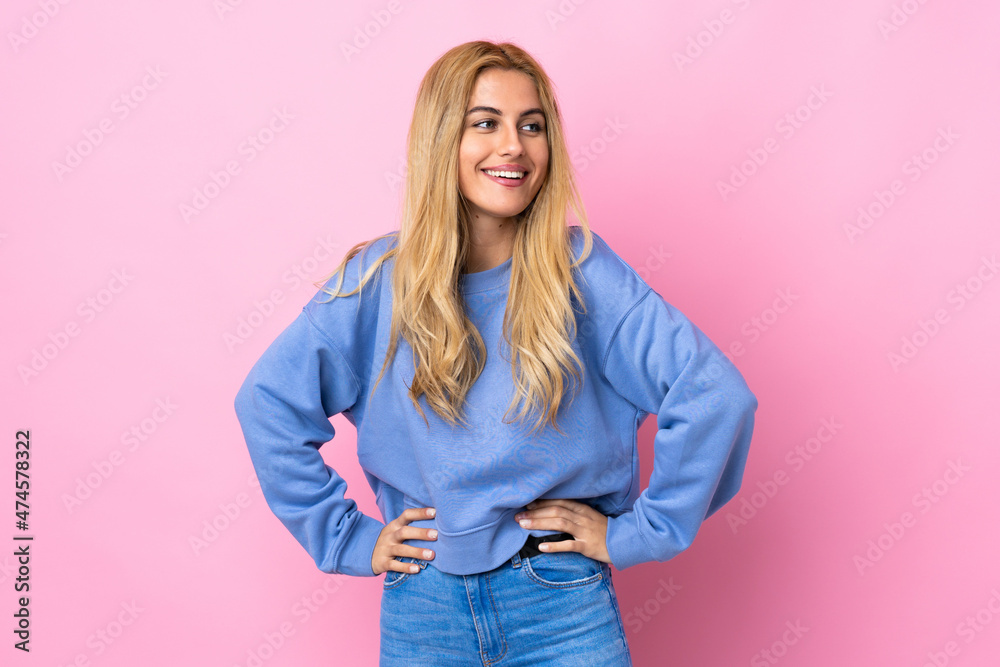 Young Uruguayan blonde woman over isolated pink background posing with arms at hip and smiling Young Uruguayan blonde woman over isolated pink background posing with arms at hip and smiling