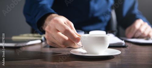 Businessman working in office and holding a cup of coffee.