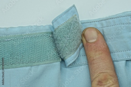 finger opens the plastic velcro on the blue fabric of the jacket sleeve