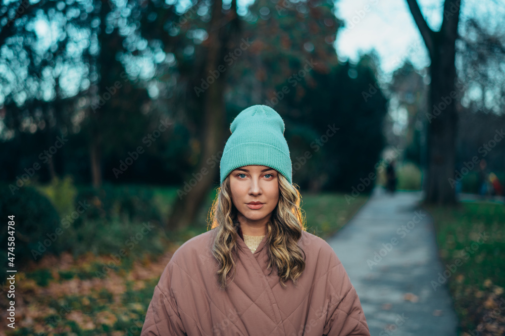 Beautiful young stylish woman wearing coat and a cap in the park Beautiful young stylish woman wearing coat and a cap in the park