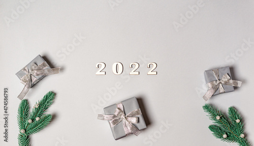 Fototapeta Naklejka Na Ścianę i Meble -  Wooden numbers 2022 with gift boxes, fir branches on a gray background with place for text.