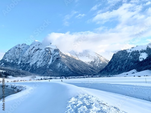Valley Studen in canton Schwyz, Switzerland on winter day. It is famous for its cross country skiing resort. There are winter hiking trails as well. On the background there are snow covered mountains.