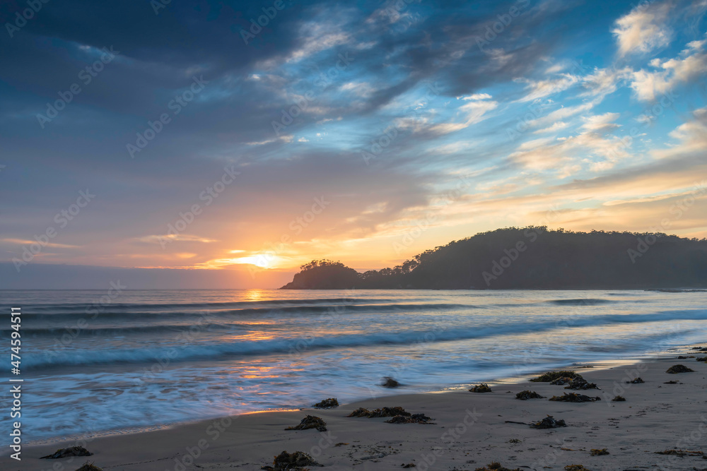 Sunrise at the seaside with cloud cover and seaweed