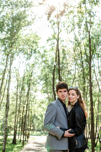 Happy young girl laughing happily while standing next to her beloved boyfriend in spring in the park. Careless young lovers enjoying romantic relaxation together