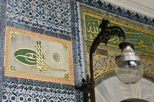 Istanbul, Turkey: A calligraphic monogram (tughra) of an Ottoman sultan is surrounded by blue and white Iznik tilework next to a lamp at Topkapi Palace, a UNESCO World Heritage Site. photo