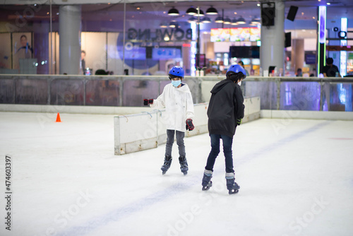 Asian teenager boy play ice skate indoor