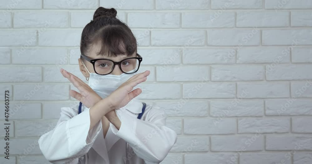 Little doctor in self isolation. A view of a little doctor showing stop gesture during pandemic time. Little doctor in self isolation. A view of a little doctor showing stop gesture during pandemic time.
