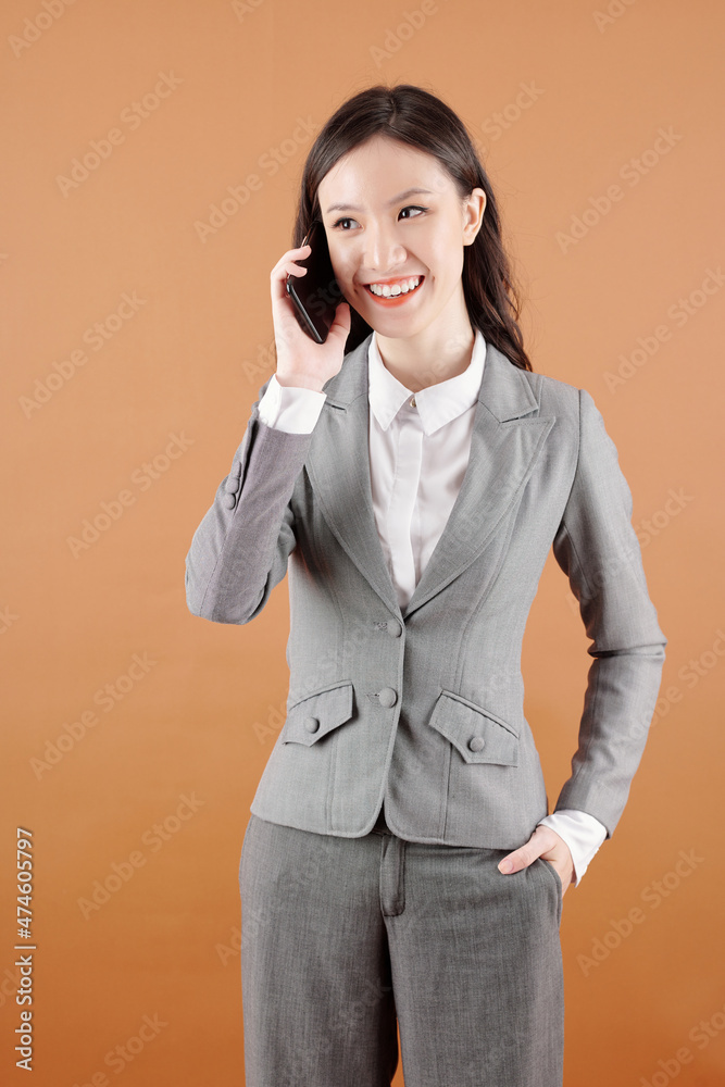 Portrait of cheerful young female entrepreneur talking on phone with colleague