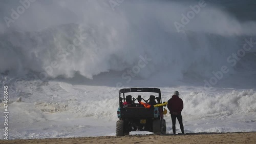 Slow motion of a wave break on the beach in Nazaré, Portugal. Rescue team watching the action. photo