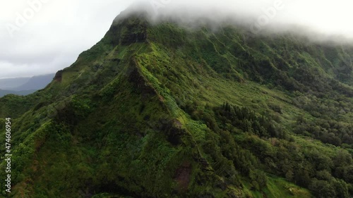 Drone rising up into the rain clouds while looking at the majestic mountain ridge in hawaii photo