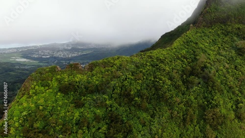 Drone flying over hawaiian mountain overlooking east oahu town on a rainy day photo