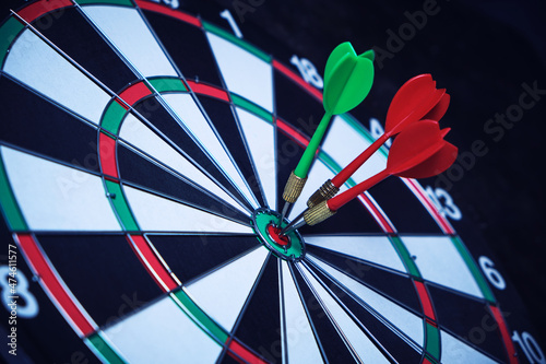 Фотография Dartboard with three darts stuck right center of the target.