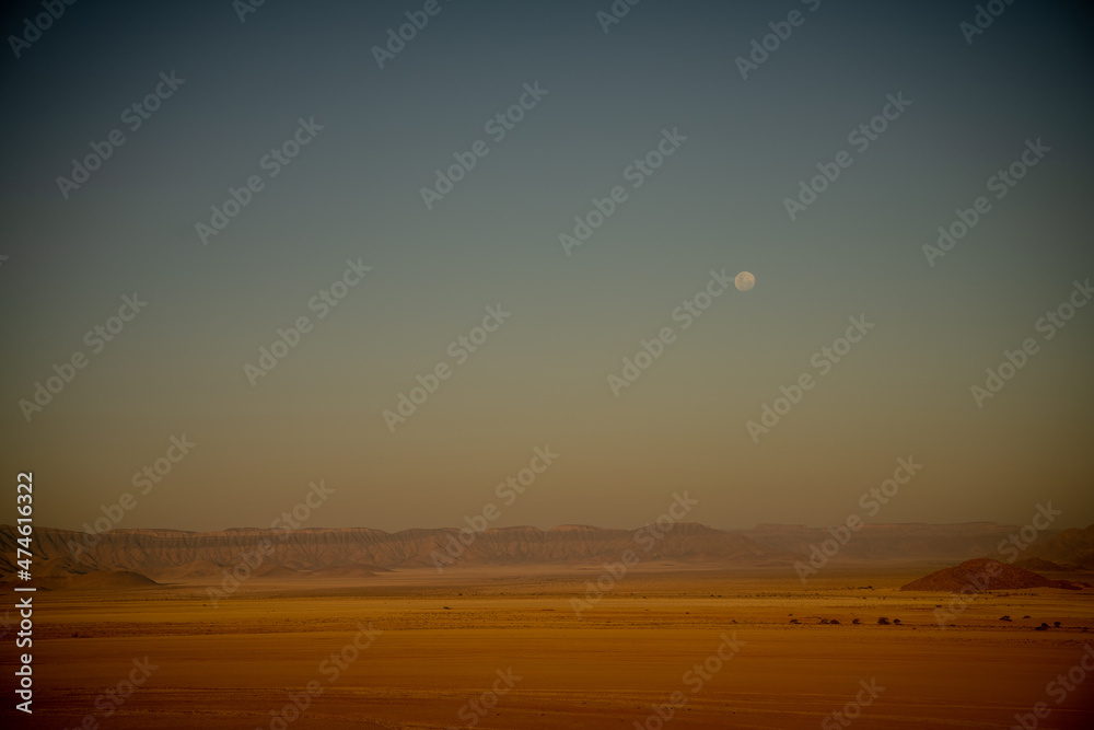 A moon visible after sunset seen from Elim Dune, Namib Desert, Namibia A moon visible after sunset seen from Elim Dune, Namib Desert, Namibia