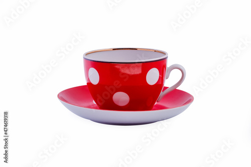 Ceramic red cup with white polka dots on saucer isolated on white background. Copy space.