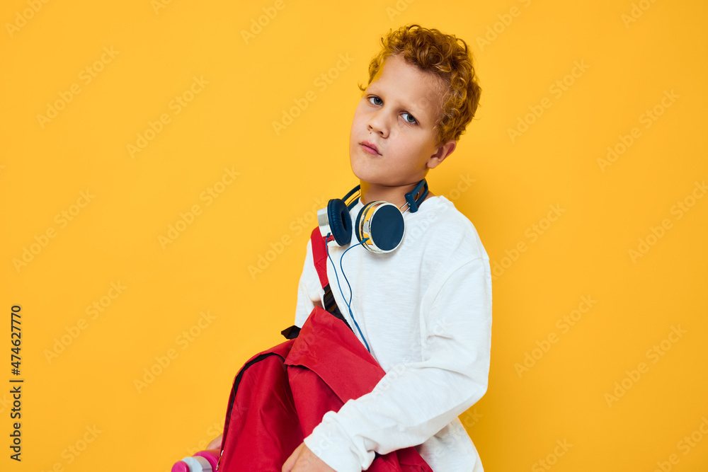 stylish boy with a red backpack wearing headphones yellow background stylish boy with a red backpack wearing headphones yellow background