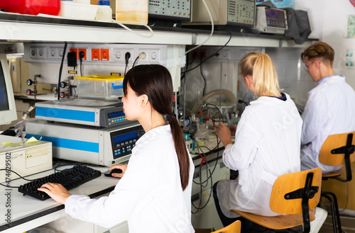 Multiracial team of students performing experiments on lab equipment in modern university research laboratory