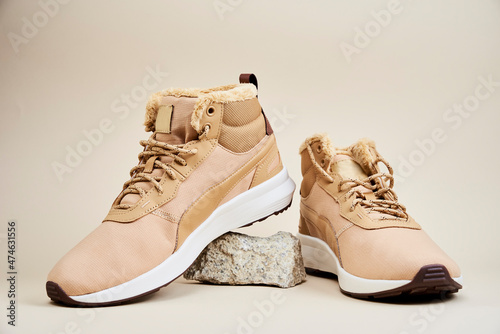 Male boots on beige background. Pair of winter shoes on stone platform photo