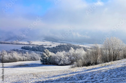 Dramatic clouds, blue sky in winter landscape with mountains and trees on field nature scenery.