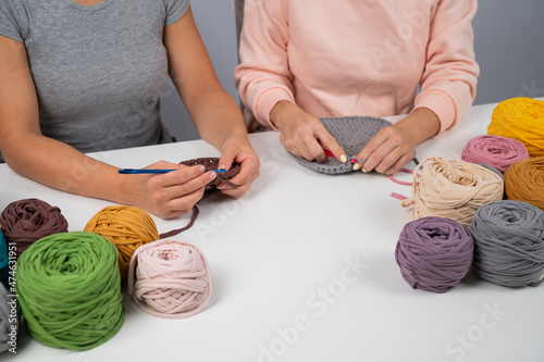 A woman teaches her friend needlework. Two women are crocheting a basket of cotton yarn. photo