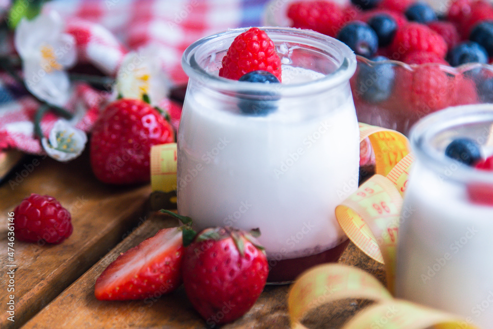 yogurt with wild berries and measuring tape. diet and eating concept yogurt with wild berries and measuring tape. diet and eating concept