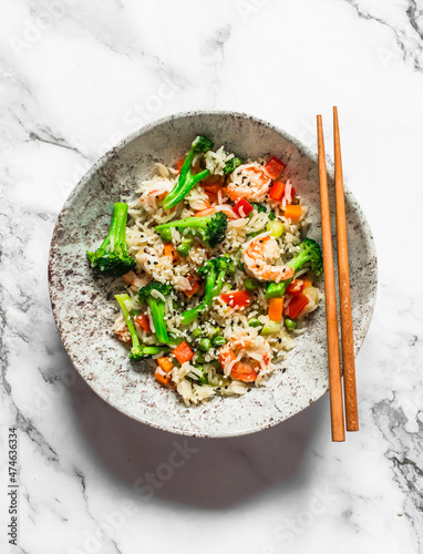 Asian style lunch - rice with shrimp and vegetables  on a light background, top view