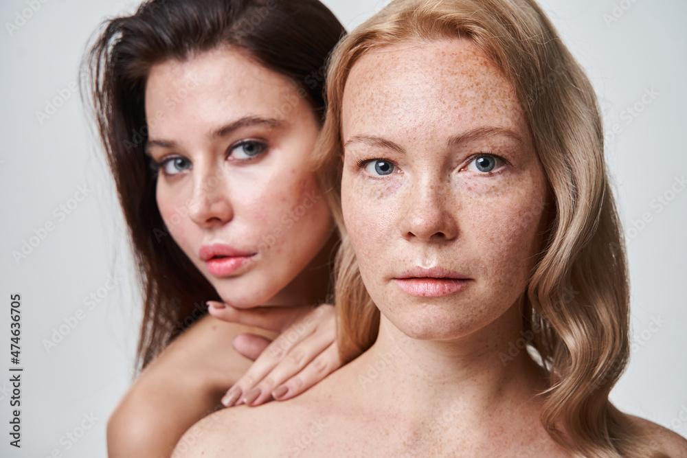 Two diverse girls standing behind of each other while posing at the studio Two diverse girls standing behind of each other while posing at the studio