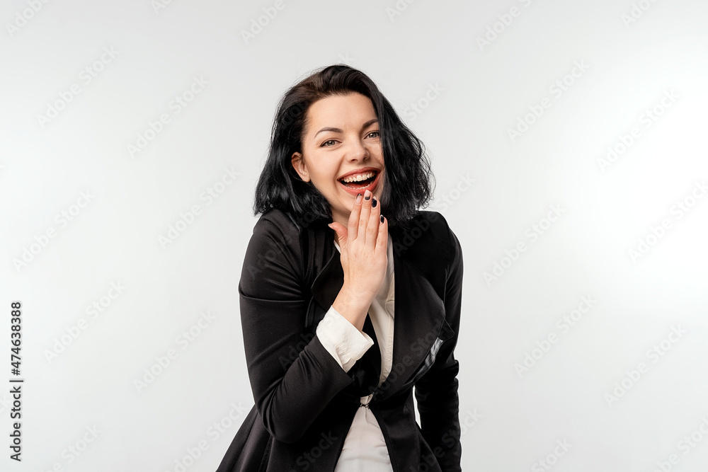 Cute young businesswoman in black formal jacket white shirt shrugging shoulders and cover her smile with palm coquettish, being coy while apologizing, white background Cute young businesswoman in black formal jacket white shirt shrugging shoulders and cover her smile with palm coquettish, being coy while apologizing, white background