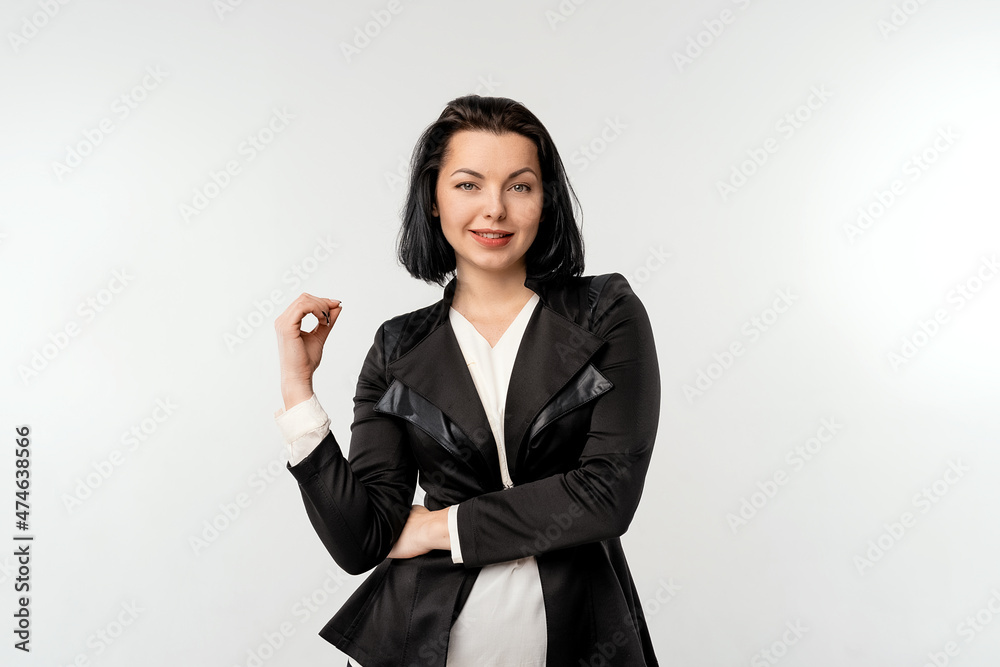 Beautiful young business woman with dark hair posing isolated over white wall background and looking at camera with a happy smile on face, wear black formal jacket white shirt Beautiful young business woman with dark hair posing isolated over white wall background and looking at camera with a happy smile on face, wear black formal jacket white shirt